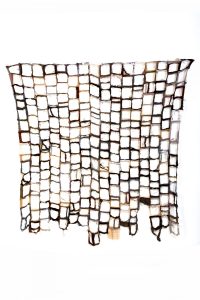 Quilt made from cloth in shades of brown with centres cut away from each small square, leaving seams only