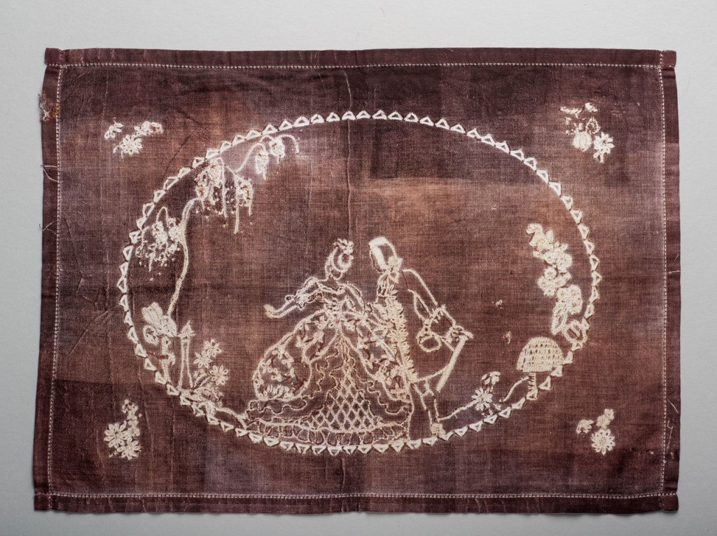 Cloth coloured red-brown with traditional embroidery unpicked leaving white lines