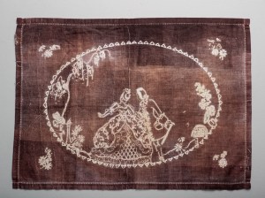 Cloth coloured red-brown with traditional embroidery unpicked leaving white lines