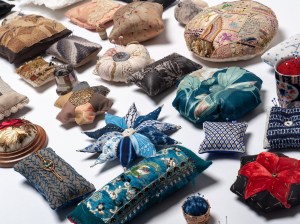 image of a group of over 25 decorative pincushions arranged for exhibition