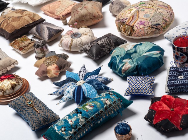 image of a group of over 25 decorative pincushions arranged for exhibition